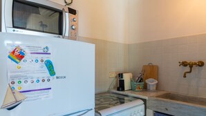 A compact kitchen with a white refrigerator, microwave, and stove.