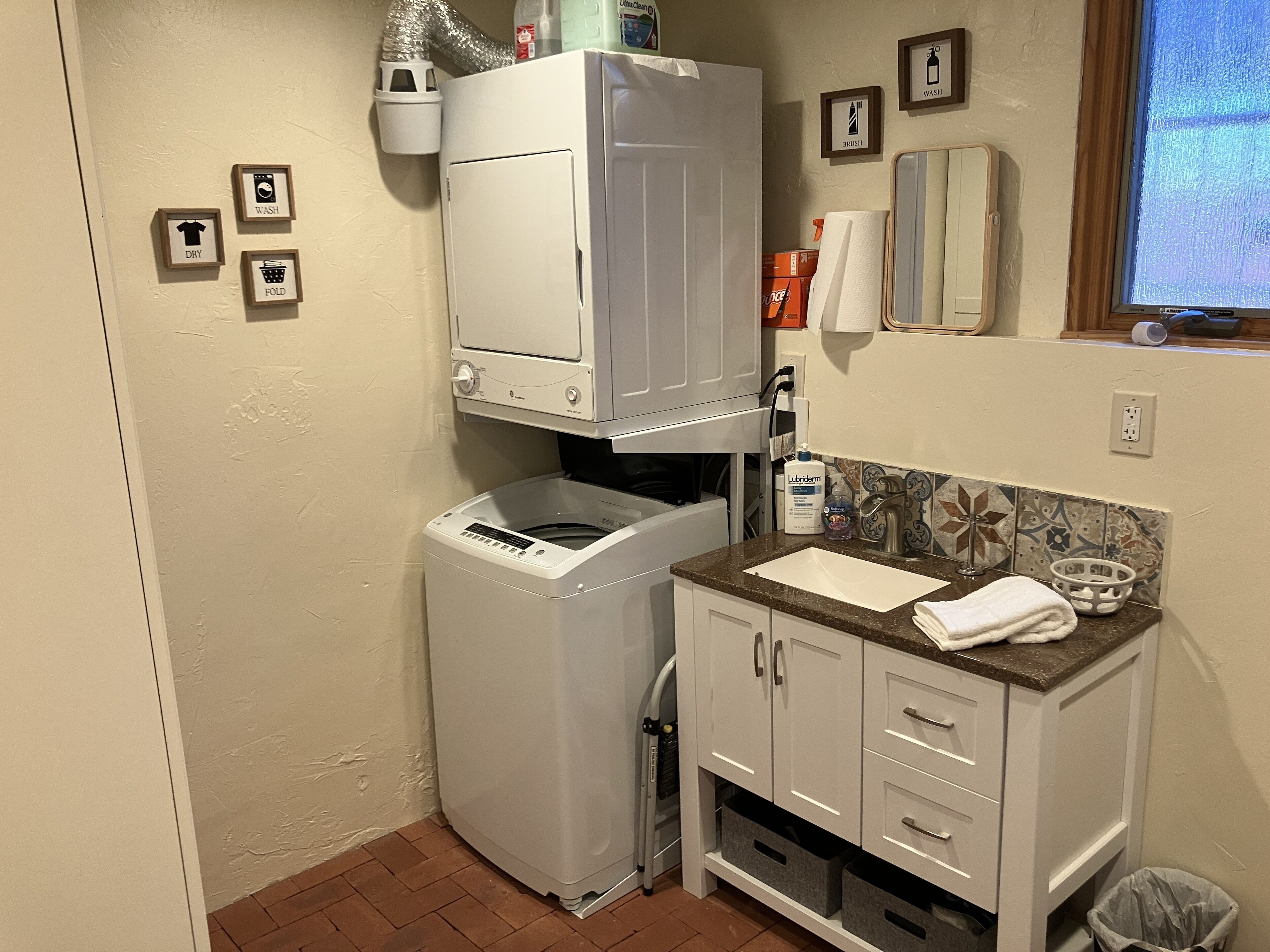 A compact laundry area with a washing machine, dryer, and a small sink with a towel.