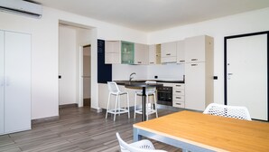 Une cuisine moderne avec un îlot central, des tabourets de bar blancs et une table à manger en bois.