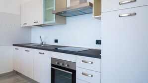 Eine moderne Küche mit weißen Schränken, einem Edelstahlbackofen und einer schwarzen Arbeitsplatte.