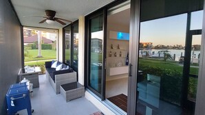 A balcony with a sofa, a small table, and a blue cart. - Bay view 1st floor condo with beach access. (Marco Island)