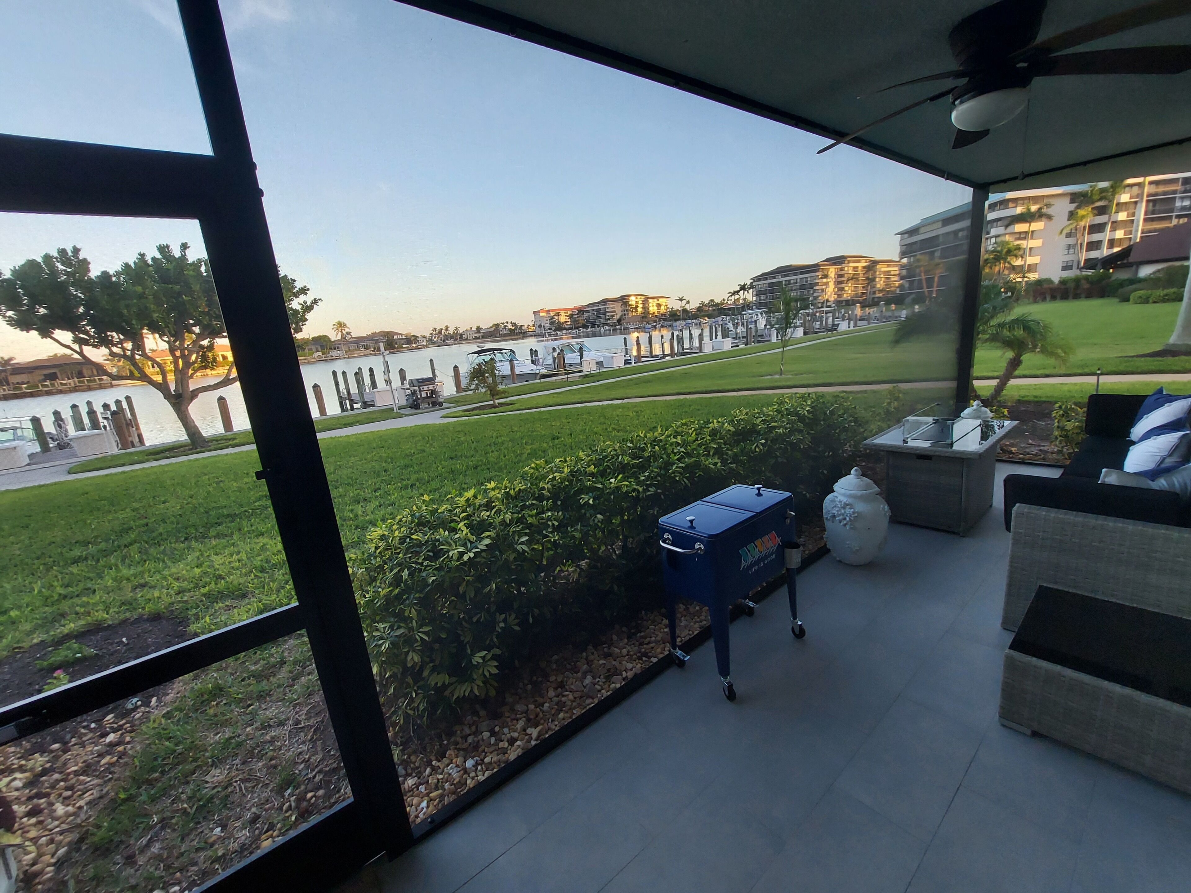 Un balcón con vista al agua, mobiliario exterior y una parrilla.