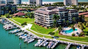 A high-rise hotel with multiple balconies, a marina with boats, and a pool area. - Bay view 1st floor condo with beach access. (Marco Island)