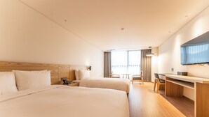 A hotel room with two beds, a desk, a chair, a TV, and a window with curtains. - Grand Moment (Busan)