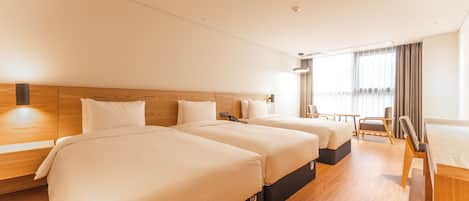 A hotel room with three beds, a desk, and a chair.