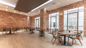 A spacious dining area with brick walls, large windows, and modern wooden furniture. - Grand Moment (Busan)