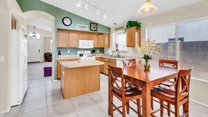 Una cocina moderna con armarios de madera, una isla central y un comedor con sillas de madera.