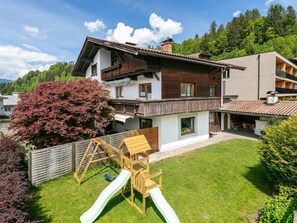 A two-story house with a wooden deck, a slide, and a fenced backyard. - Combinable apartment at only 1.3 km to the ski lift (Hopfgarten im Brixental)