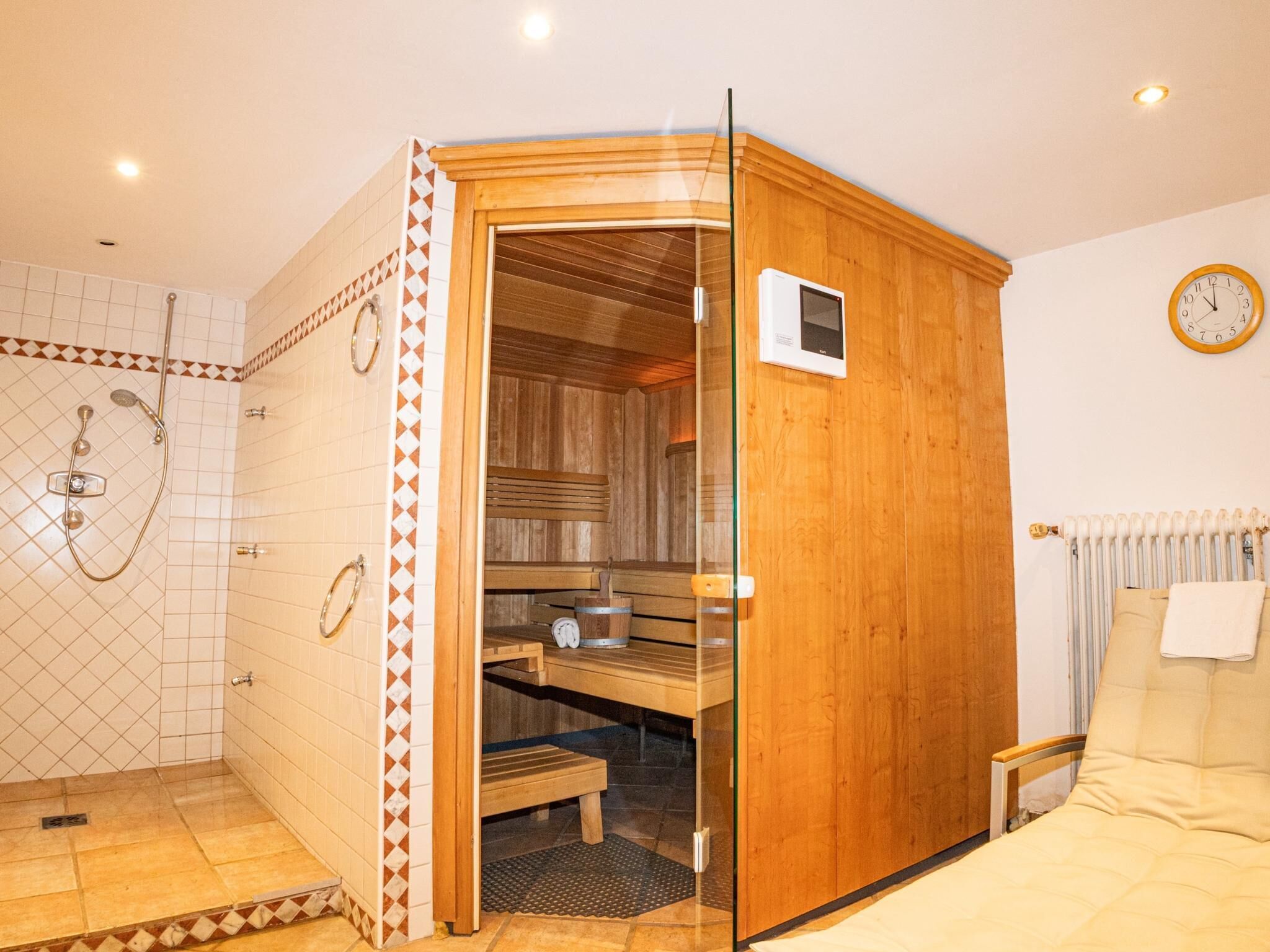 Ein Saunaraum mit Holztür, einer Sitzbank und einem Duschbereich mit Glastür.