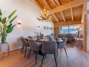 A dining area with a wooden ceiling, a chandelier, and a view of the outdoors.