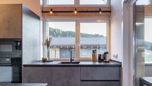 Une cuisine moderne dotée d’une grande fenêtre, d’un four encastré et d’un plan de travail en bois.