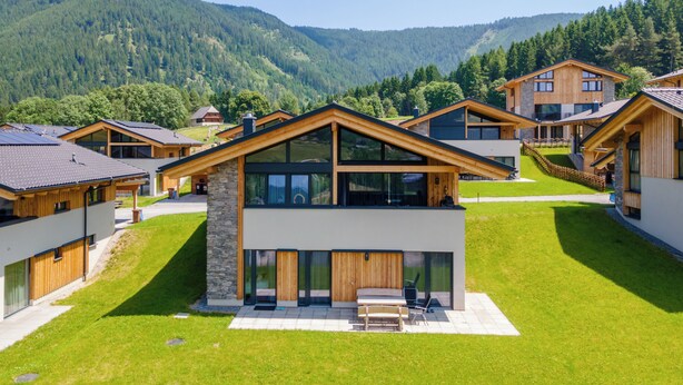 A modern chalet with a stone facade, large windows, and a wooden deck. - Lovely ski in-ski out lodge with sauna (Sankt Lambrecht)