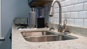 A kitchen with a stainless steel sink, a modern faucet, and a coffee maker. - Cozy Cottage within walking distance of downtown! (Bristol)