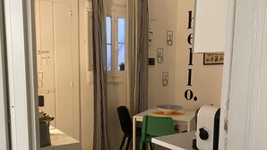 Una cocina funcional con una mesa, sillas, una lámpara colgante y un ventanal con cortinas.