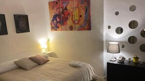Una habitación de hotel con una cama, un cuadro, una lámpara y una pared con formas circulares.