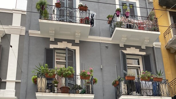 Un edificio de varios pisos con balcones decorados con macetas.