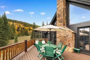 A wooden deck with a table and chairs, a stone wall, and a view of a forested mountain. - The Sunflower-Secluded luxury,hot tub,minutes to town (Skyland & Surrounding Areas)
