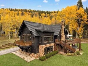 A modern house with a stone foundation, a large deck, and a prominent chimney. - The Sunflower-Secluded luxury,hot tub,minutes to town (Skyland & Surrounding Areas)