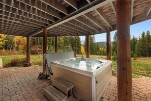 Ein Whirlpool unter einer hölzernen Pergola mit Blick auf einen Wald und Berge.
