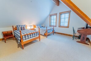 Un dormitorio con dos camas de madera, un escritorio y dos ventanas.