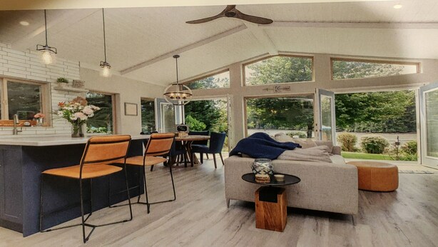 A spacious living area with a large window, a dining area with chairs, a sofa, and a small table. - ocean dock and pool art villa  (Ladysmith)