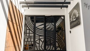 Ein moderner Eingangsbereich mit einem geometrischen Metallgitter, einer Holzwand links und einem an der Wand befestigten Schild.