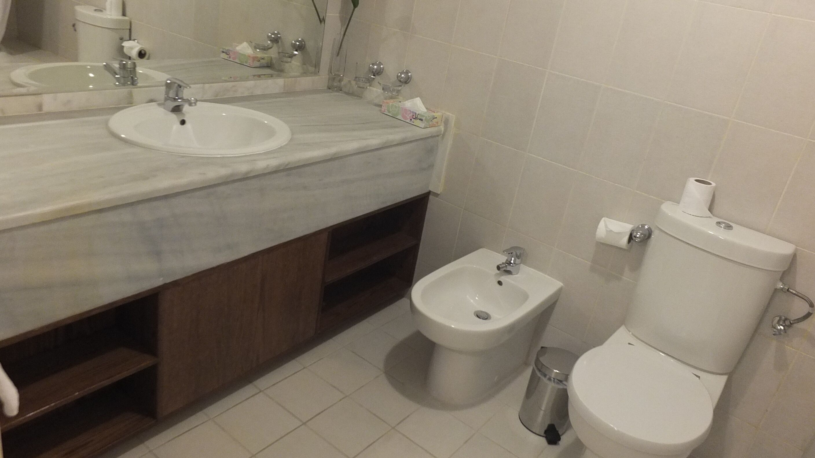 A bathroom with two sinks, a bidet, and a toilet.
