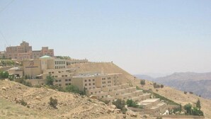 A hotel with multiple buildings on a hillside, featuring a prominent sign with a logo. - Petra Panorama Hotel (Wadi Musa)