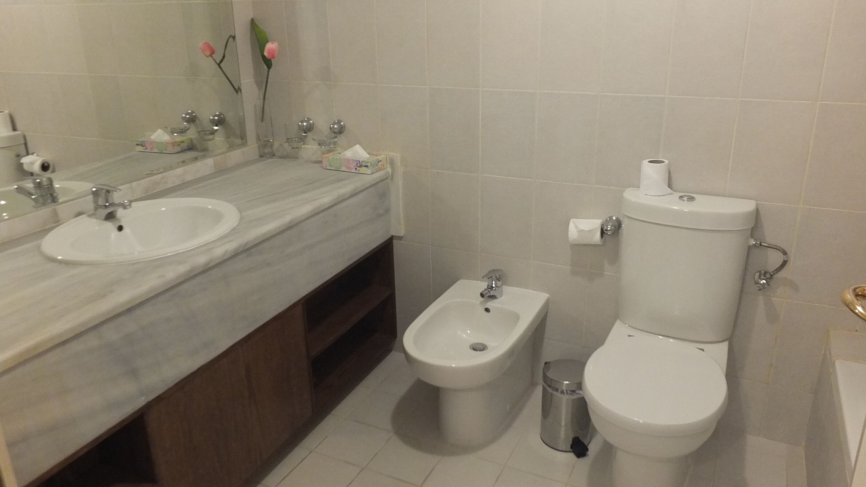 Un bagno con due lavandini, un bidet, un water e un cestino.
