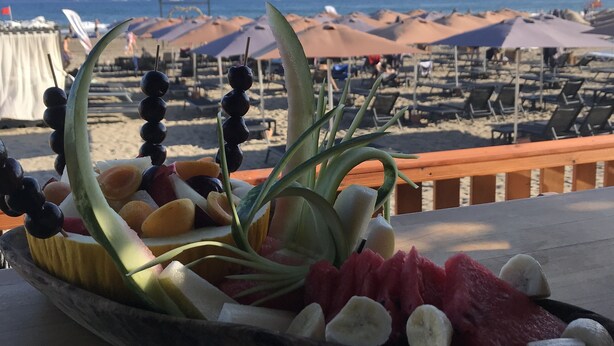 A beachside view with a table displaying a fruit platter. - Dolphin Park Hotel (Ortaca)