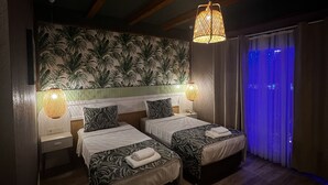 A hotel room with two beds, a patterned wall, and a ceiling with exposed beams. - Dolphin Park Hotel (Ortaca)