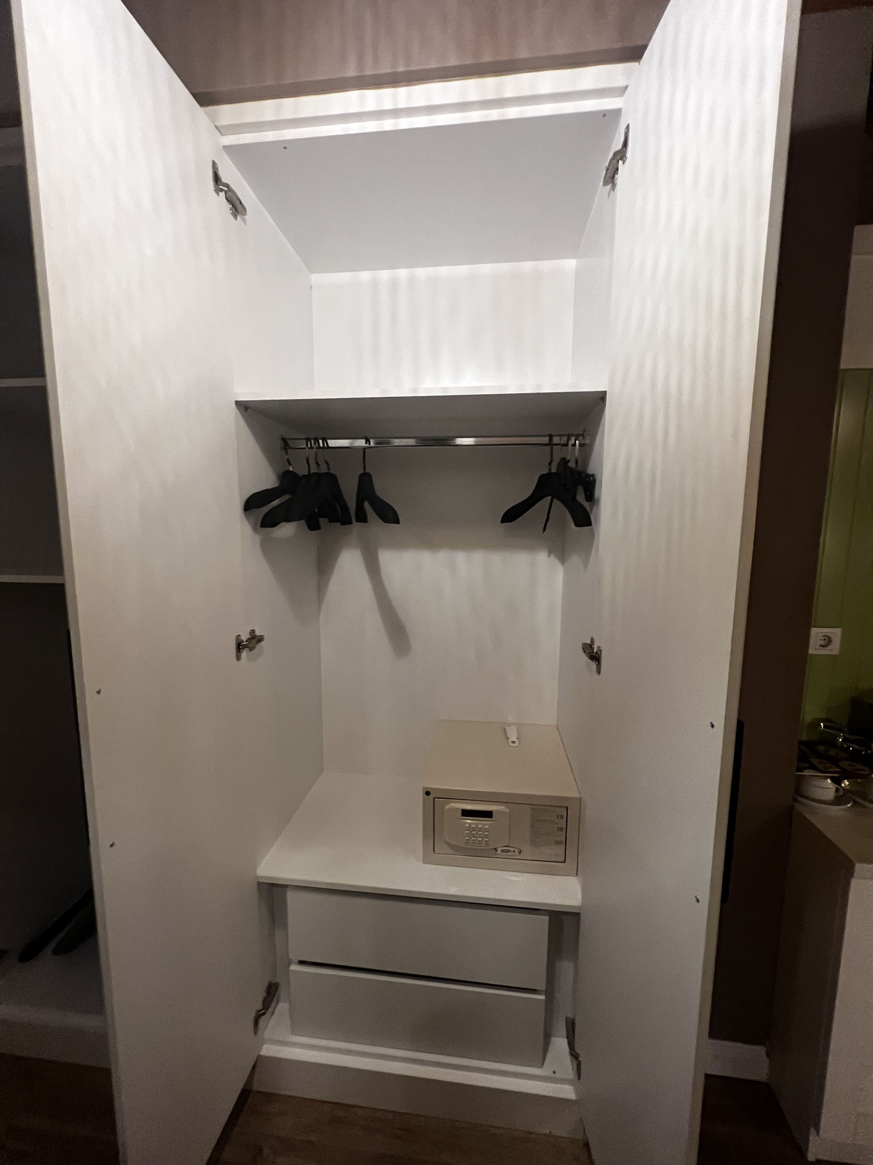 Un armario vestidor con barra para colgar, estantes y un mueble de almacenaje empotrado.