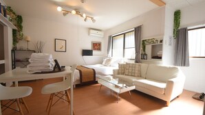 A modern living room with a white sofa, a glass coffee table, and a dining area with white chairs. - Comfy Stay MR2 (Nara)