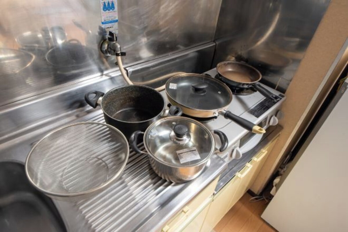 A stainless steel kitchen with four pots and pans, a griddle, and a gas stove.
