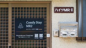 A hotel entrance with a sign for Comfy Stay MR2, a QR code, and a utility box. - Comfy Stay MR2 (Nara)