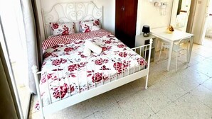 Um quarto com cama, escrivaninha e guarda-roupa.