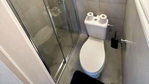 Um banheiro pequeno e compacto com box de vidro, vaso sanitário e toalha pendurada na parede.