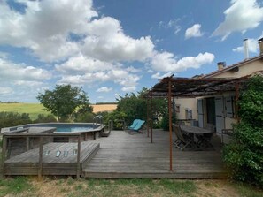 A wooden deck with a hot tub, a covered seating area, and a view of the countryside. - 🌸 L'Oasis Vacation Rental (Grazac)