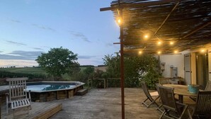 Un terrazzo in legno con idromassaggio, zona salotto all'aperto e un pergolato con luci.