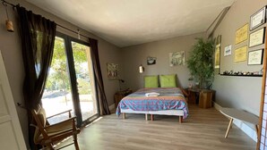 Una camera da letto con un letto, una sedia, una scrivania, una pianta e dei certificati appesi al muro.