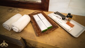 Ein Badezimmer-Waschtisch mit einer Holzschale, die ein Dentalset, zwei zusammengerollte Handtücher und eine Seifenschale mit Flaschen enthält.