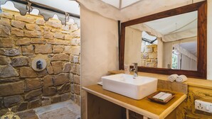 Ein Badezimmer mit Steinwand, Waschbecken, Holzausstattung und Spiegel.