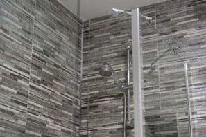 Eine Dusche mit Glasabtrennung und Regendusche.