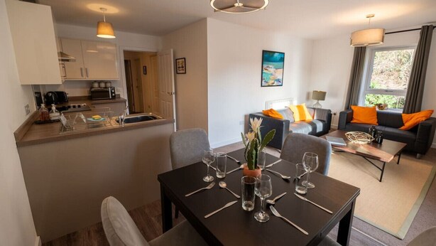 Une chambre d’hôtel moderne dotée d’un coin repas, d’une cuisine et d’un espace de vie.