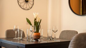 Une table à manger dressée avec des verres à vin et un centre de table composé d’un cactus orné de fleurs blanches.