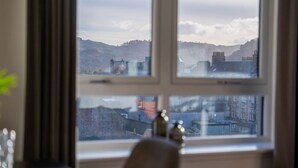 A room with a large window overlooking a cityscape with buildings and hills.