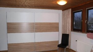 A room with a wooden ceiling, a black chair, a sliding door, and a window with a view of trees. - Apartment Bodensdorf near Gerlitzen Ski Area (Bodensdorf am Ossiachersee)