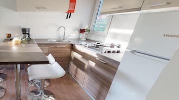 A modern kitchen with wooden cabinets, a stainless steel refrigerator, and a bar stool.