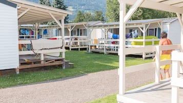 A row of mobile homes with outdoor seating areas and a view of the mountains in the background.