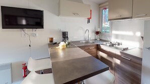 A modern kitchen with a flat-screen TV, a coffee maker, and a sink.